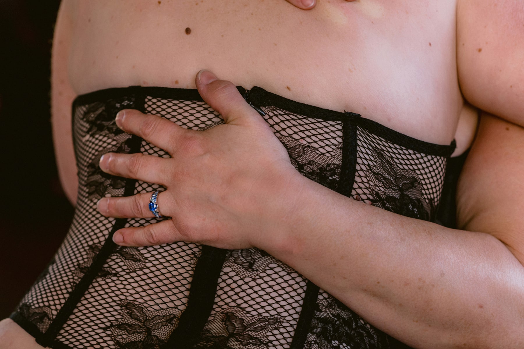 Closeup detail of newly engaged woman's hand and ring on partner's back