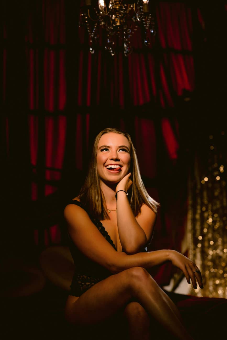 Empowering boudoir photo of a woman in an Intimissimi bodysuit with her tongue out, smiling