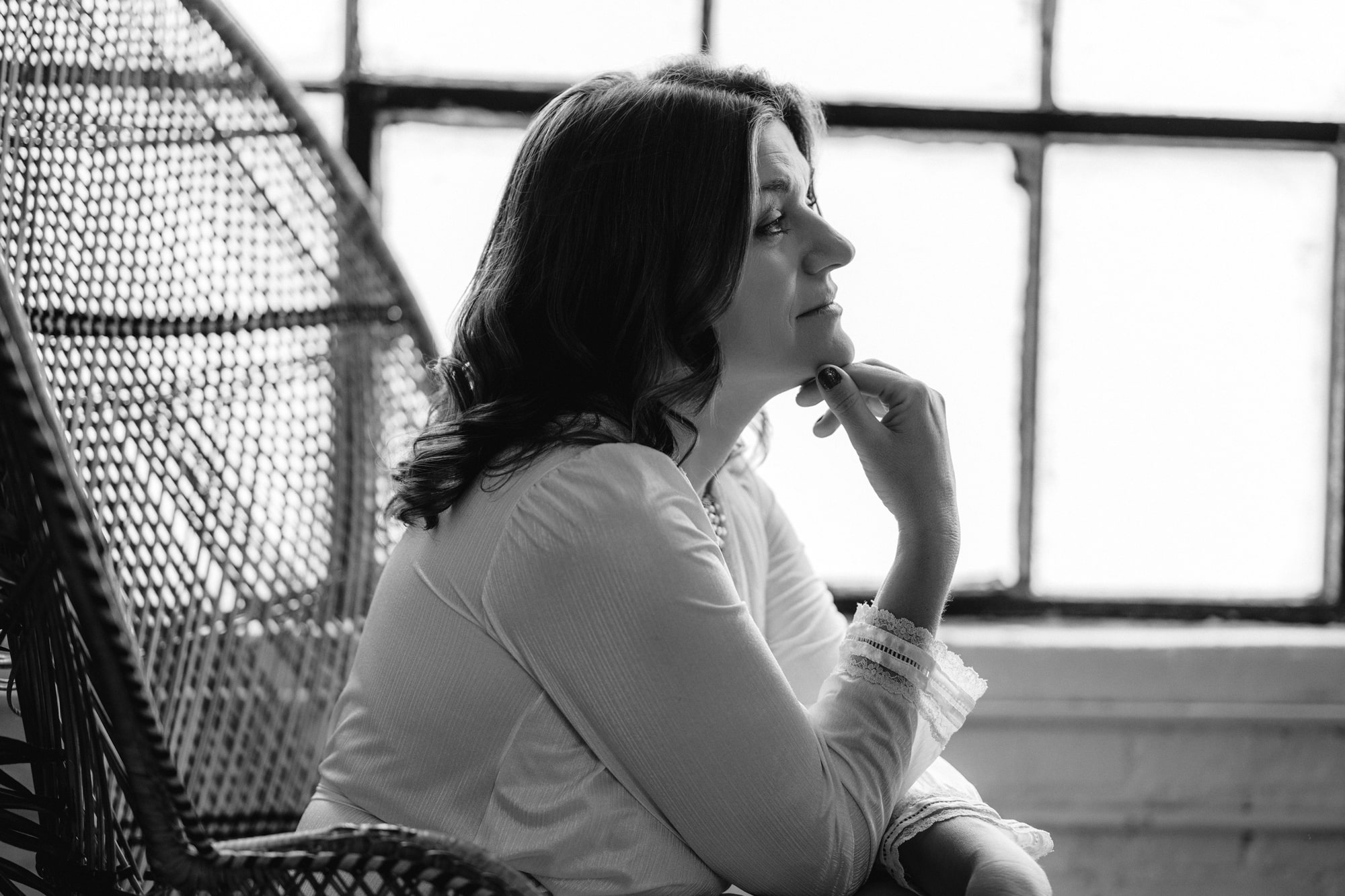Black and white profile of a beautiful mother sitting in contemplation. 
