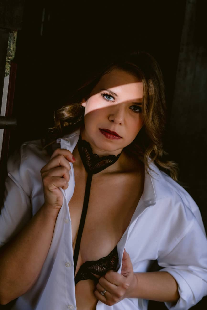 Bowie inspired boudoir photo of a woman in lingerie and a white button down shirt, with a strip of light across her eye