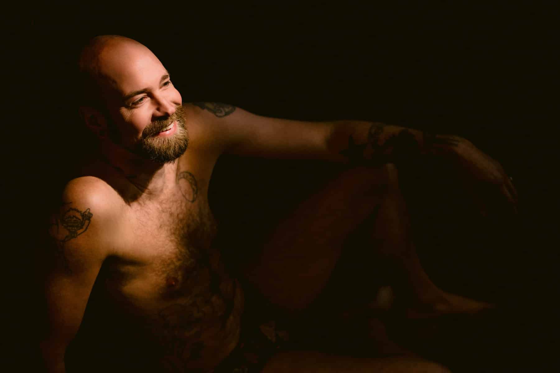 Men's boudoir, bold lighting, big smile with beard