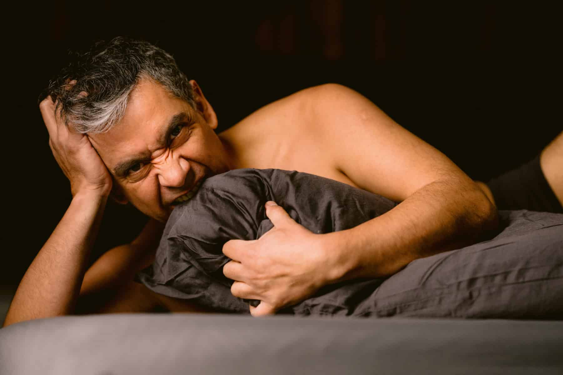 Confident Latino man posing for a men’s boudoir photoshoot, embracing his body and self-expression.”