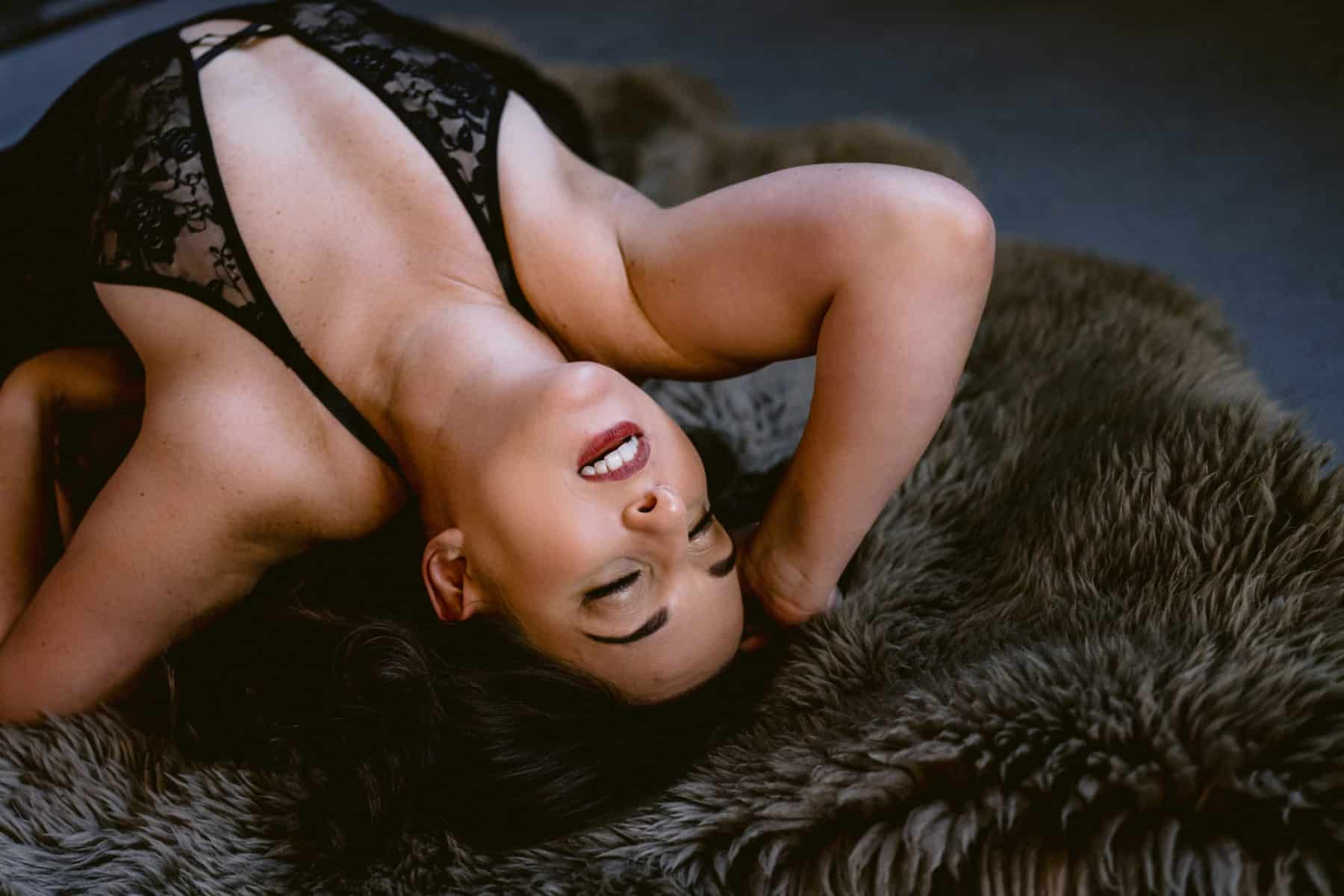 Boudoir style photo of woman arched back on the floor with her hand in her hair